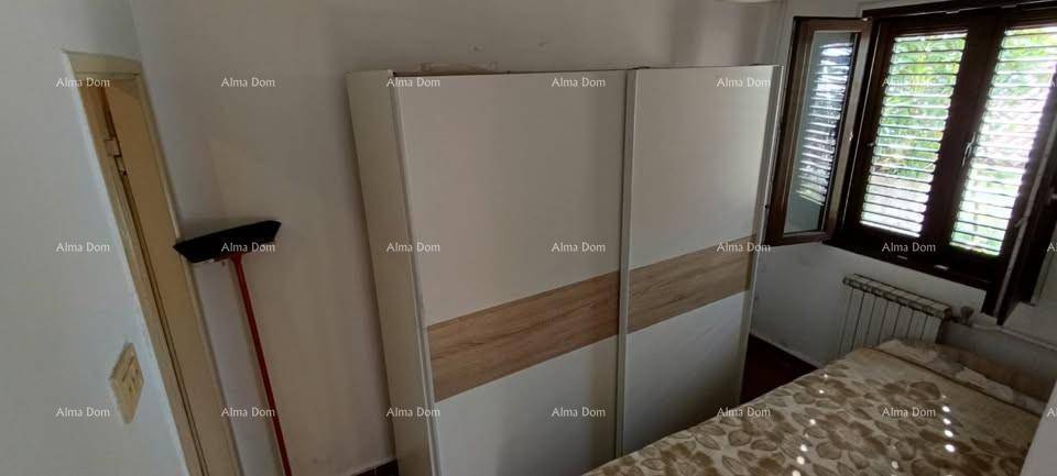 Schlafzimmer mit Kleiderschrank, Bett, Fenster mit Jalousien und Heizkörper.