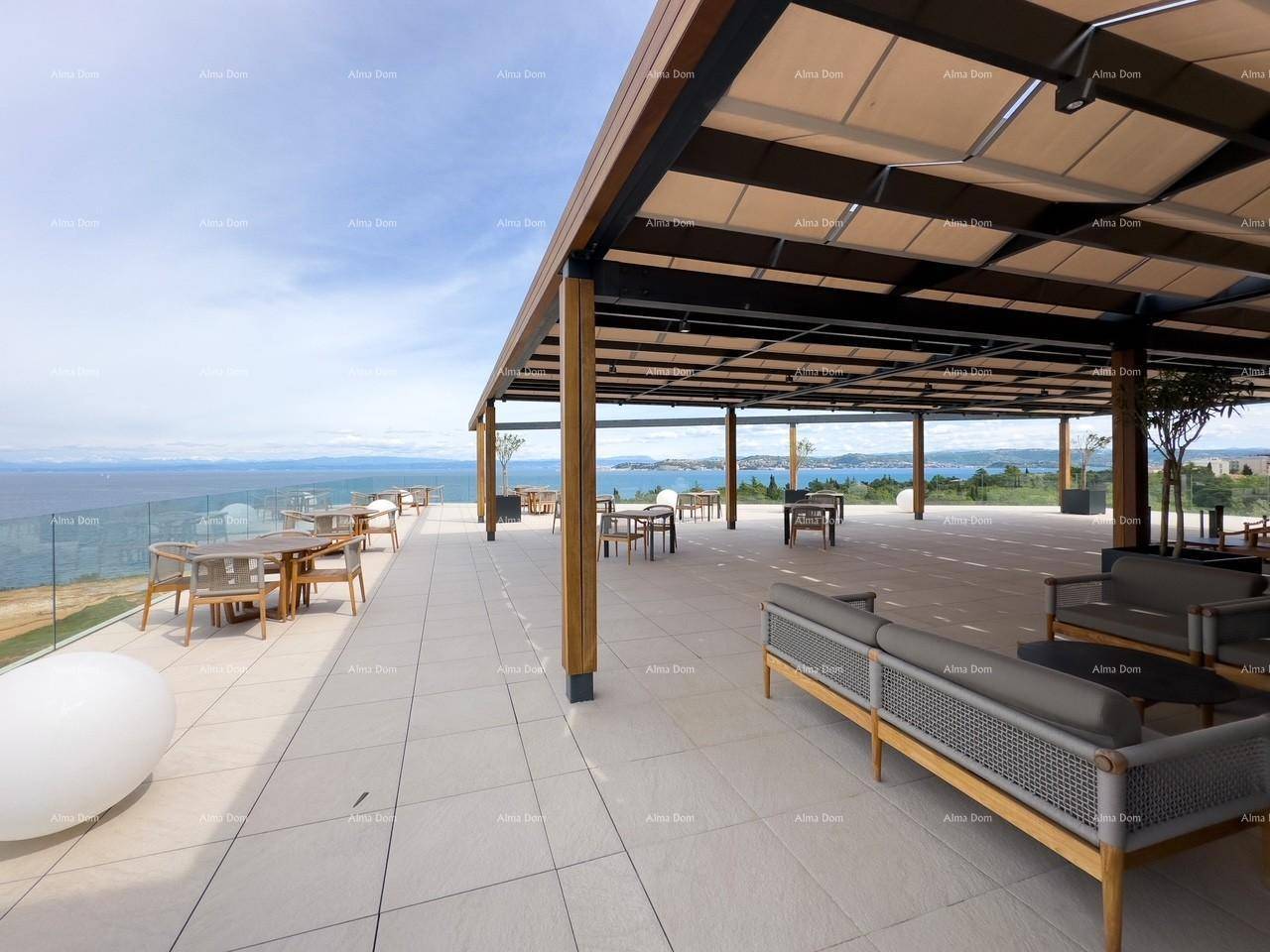 Weitläufige Terrasse mit bequemen Lounge-Möbeln und Esstischen unter einer Pergola, mit Panoramablick auf das Meer.