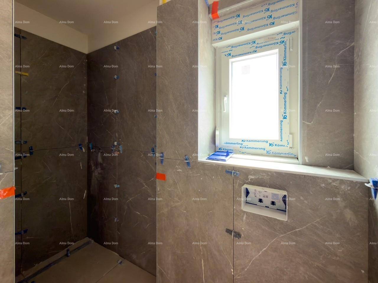 Detailansicht eines Badezimmers im Rohbau mit grauen Fliesen und vorbereiteten Anschlüssen für Sanitäranlagen.