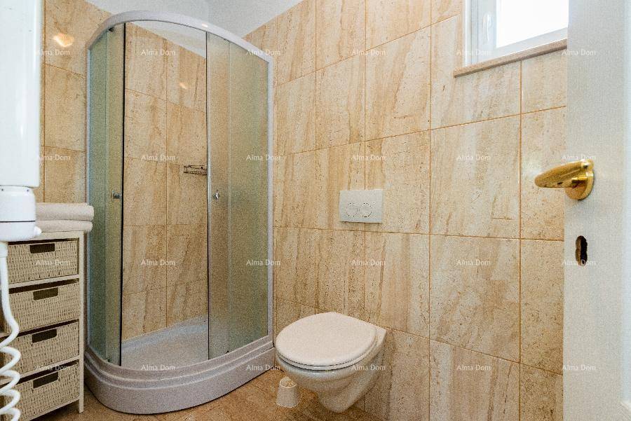 Badezimmer mit Duschkabine, WC und warmen beigefarbenen Fliesen.