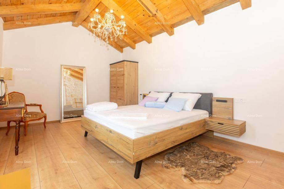 Schlafzimmer mit sichtbarer Holzbalkendecke, Parkettboden und modernem Bett.