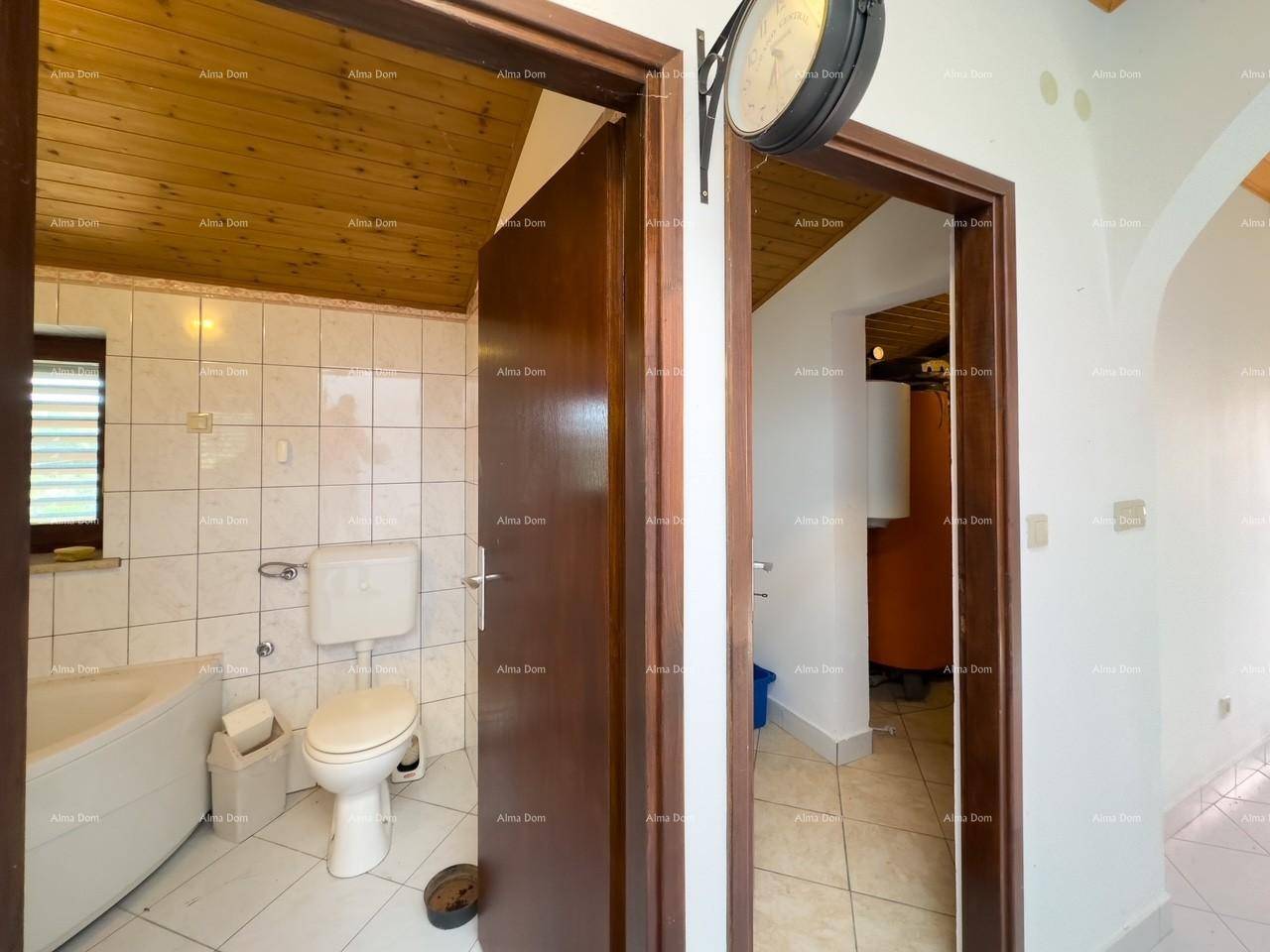 Badezimmer mit Toilette und Badewanne, durch eine offene Tür sichtbar.