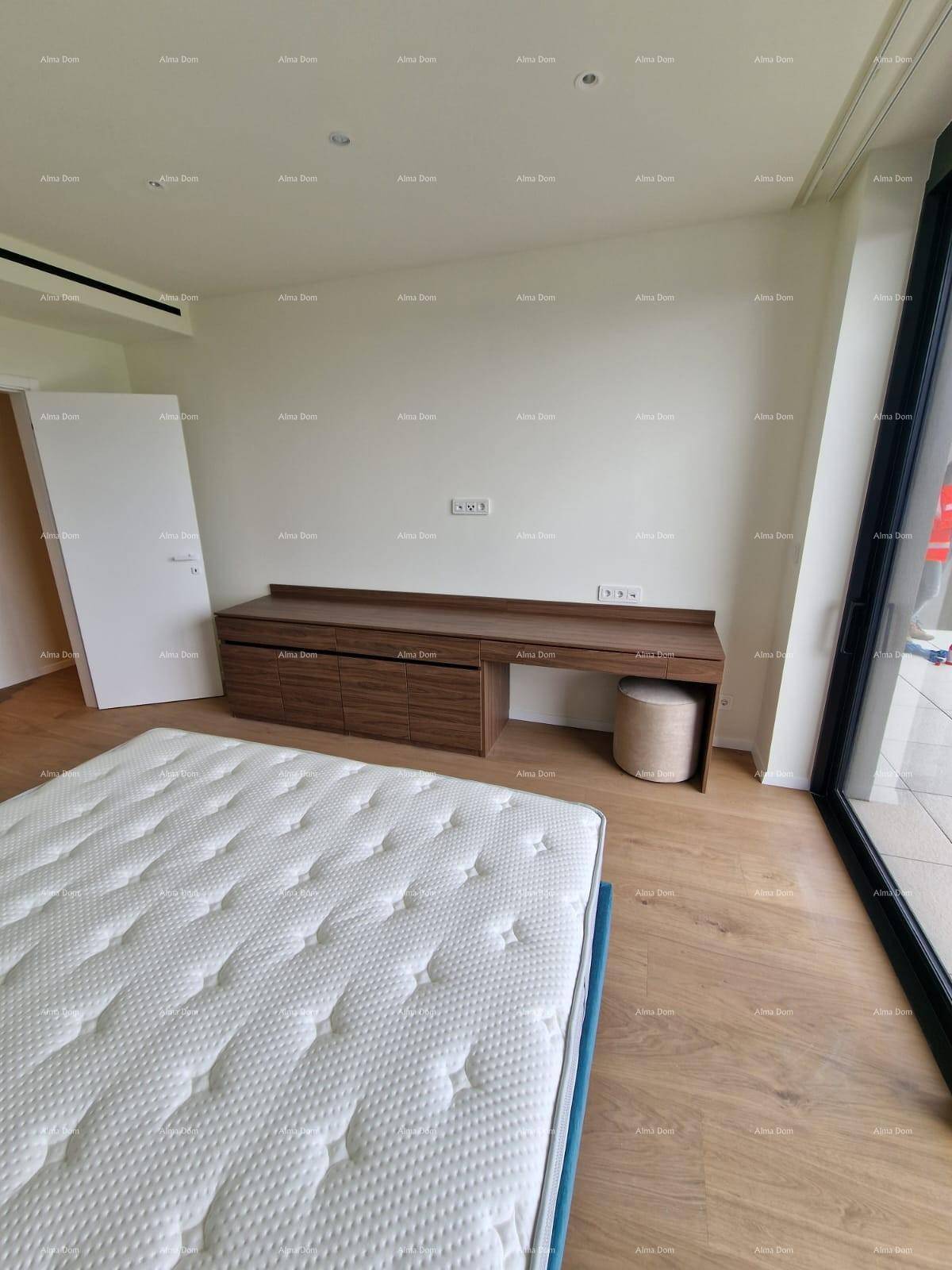 Schlafzimmer mit Holzboden, integriertem Schreibtisch und großen Fenstern für viel Licht.