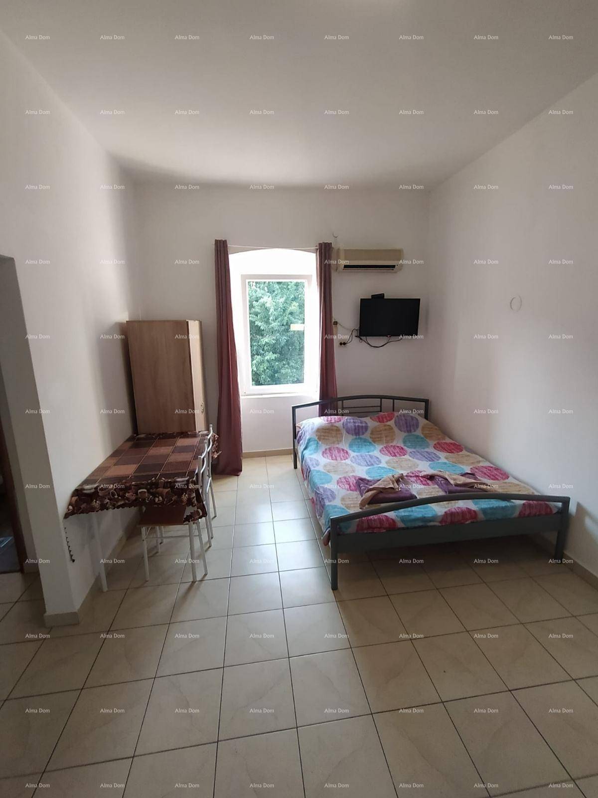 Helles Schlafzimmer in einem Studio-Apartment mit Einzelbett, Schrank und Blick ins Grüne.