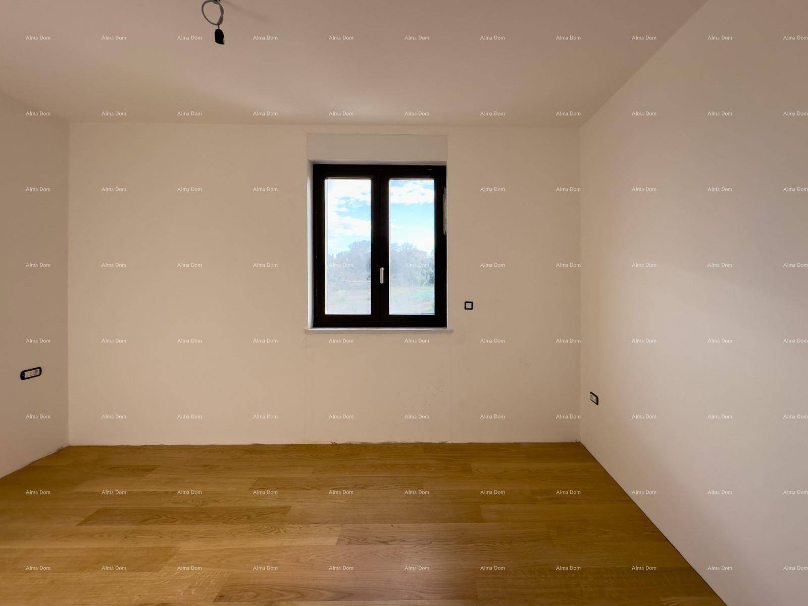 Schlafzimmer im Rohbau mit Holzboden und einem Fenster, das viel Licht hereinlässt.