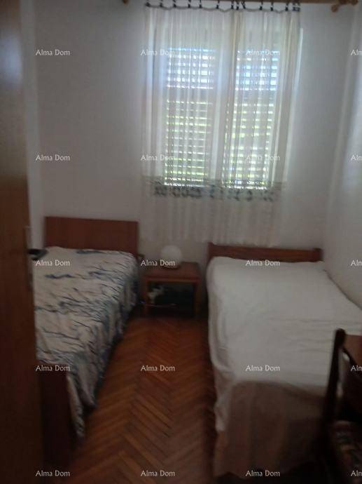 Schlafzimmer mit zwei Einzelbetten, Parkettboden und einem Fenster mit Jalousien.