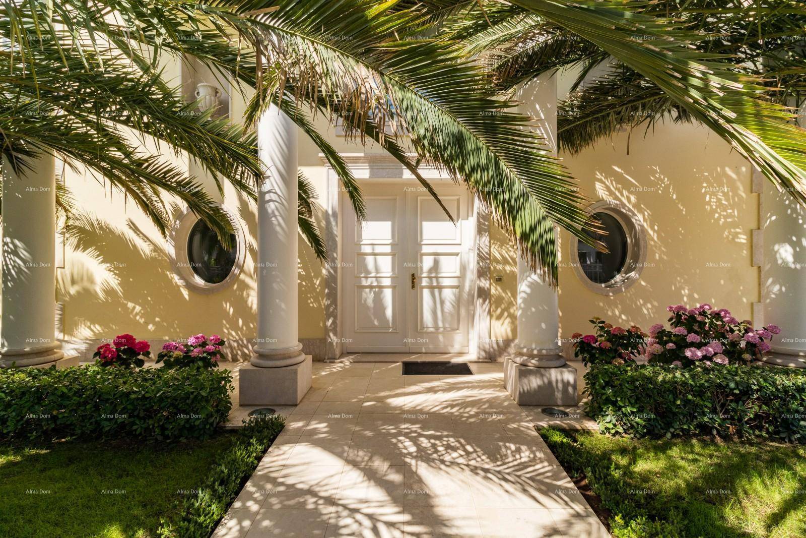 Prunkvoller Eingangsbereich der Villa mit Säulen, doppelter Tür und üppiger Bepflanzung.