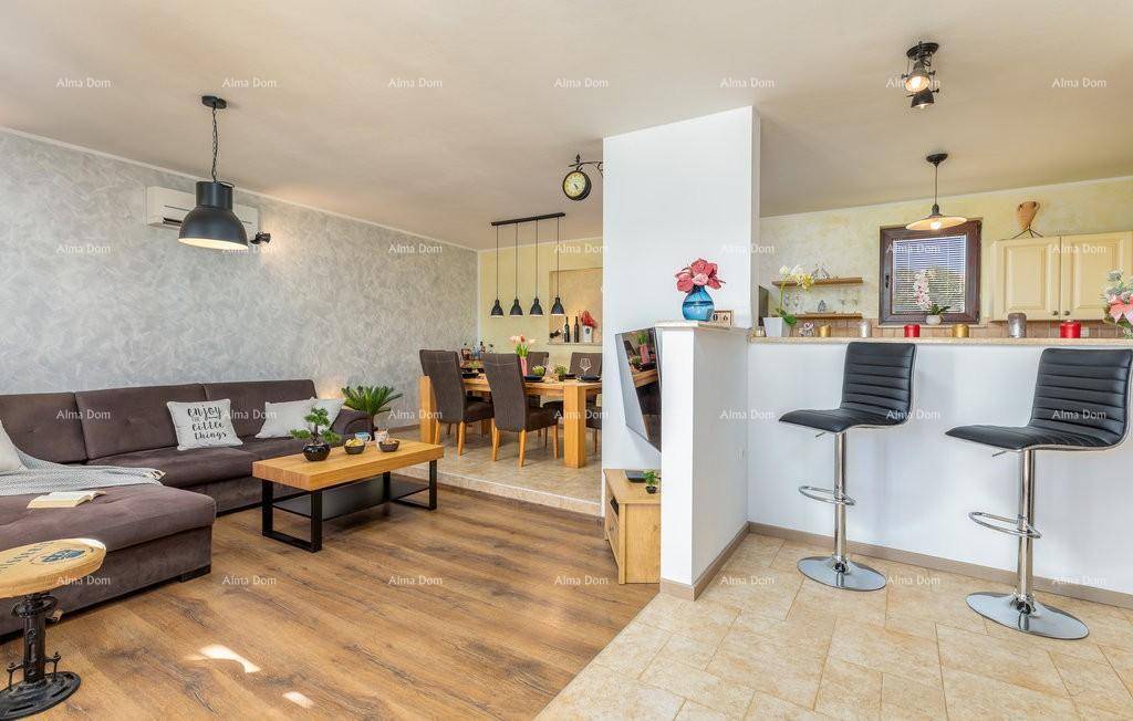 Offener Wohnbereich mit Sofa, Essbereich und einer Frühstücksbar, die zur Küche führt.