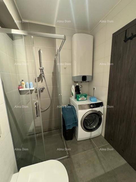 Funktionales Badezimmer mit Duschkabine, Waschmaschine und Warmwasserboiler.