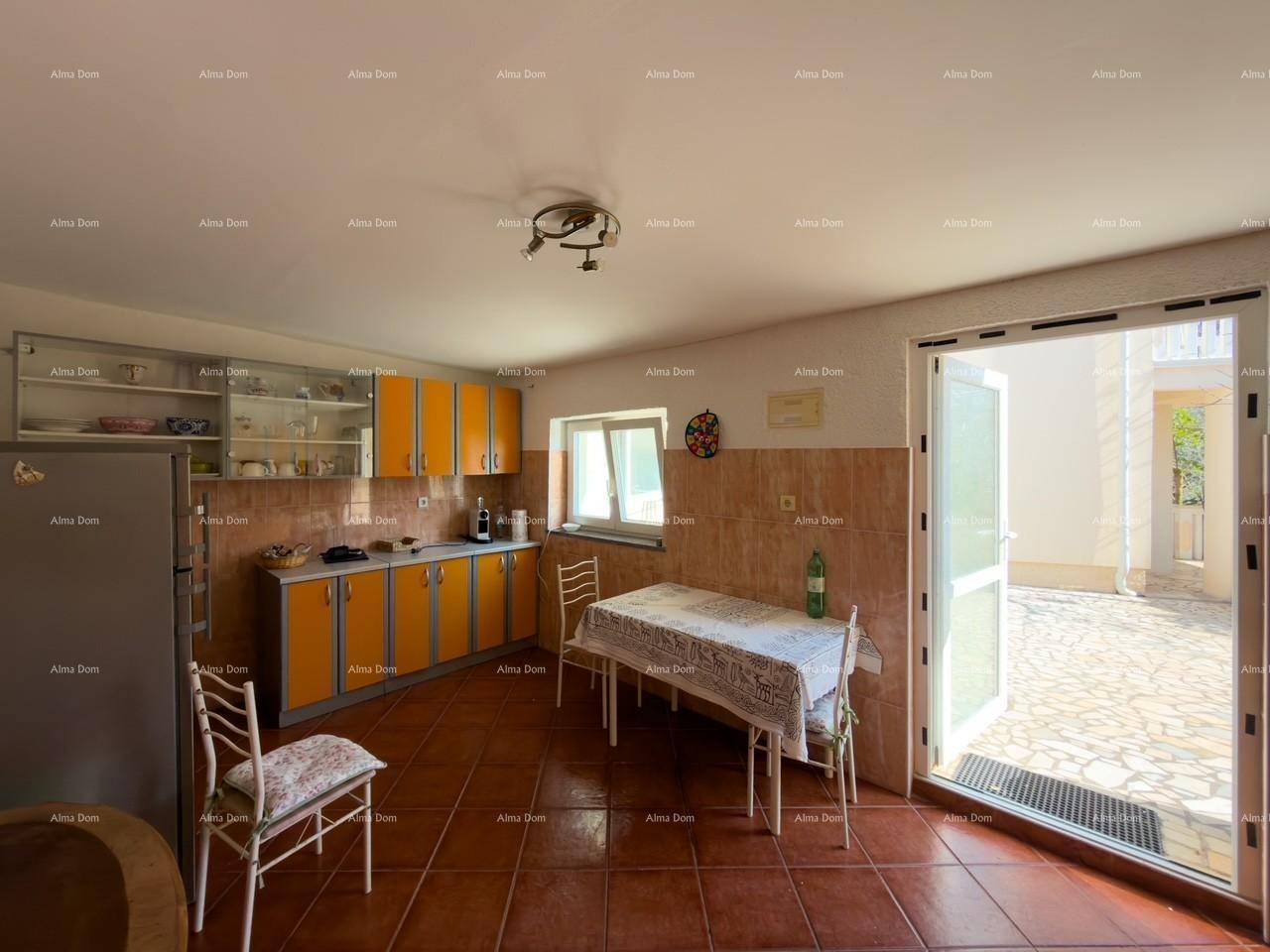 Geräumige Küche mit orangefarbenen Schränken, Esstisch und direktem Zugang zur Terrasse.