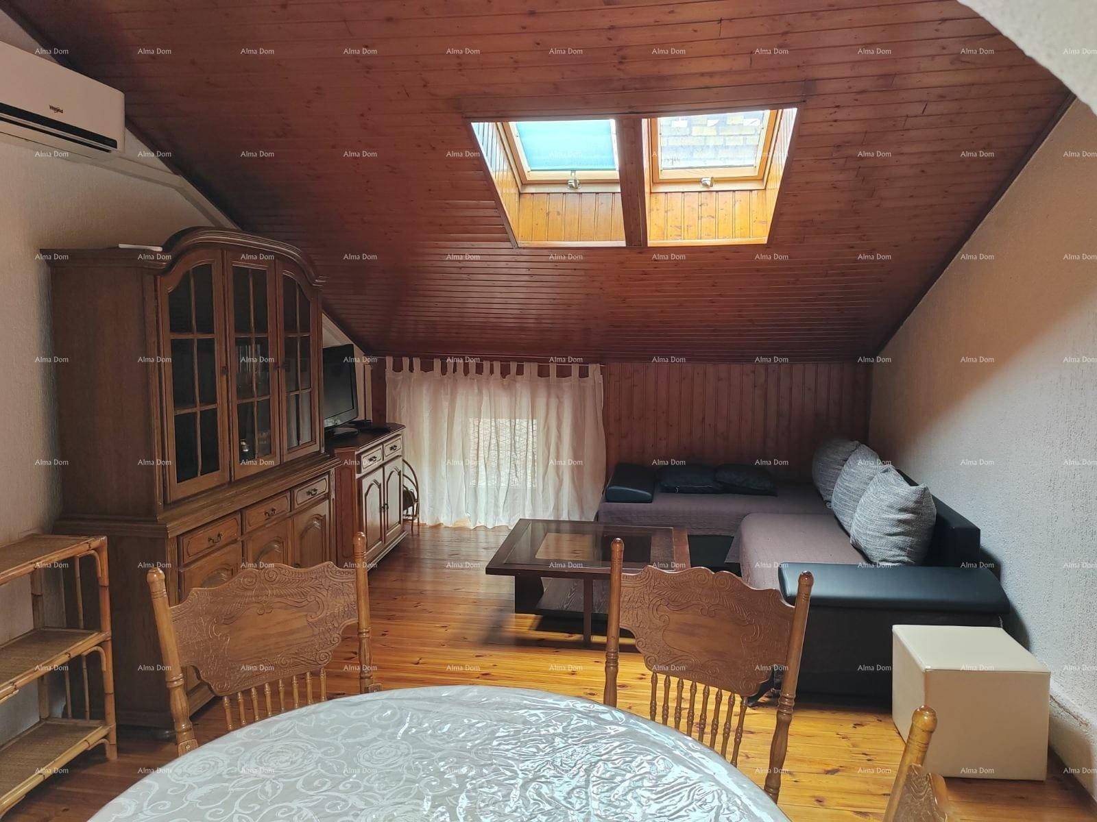 Gemütlicher Wohn- und Essbereich im Dachgeschoss mit Holzbalkendecke, Holzboden, Sofa und Esstisch.