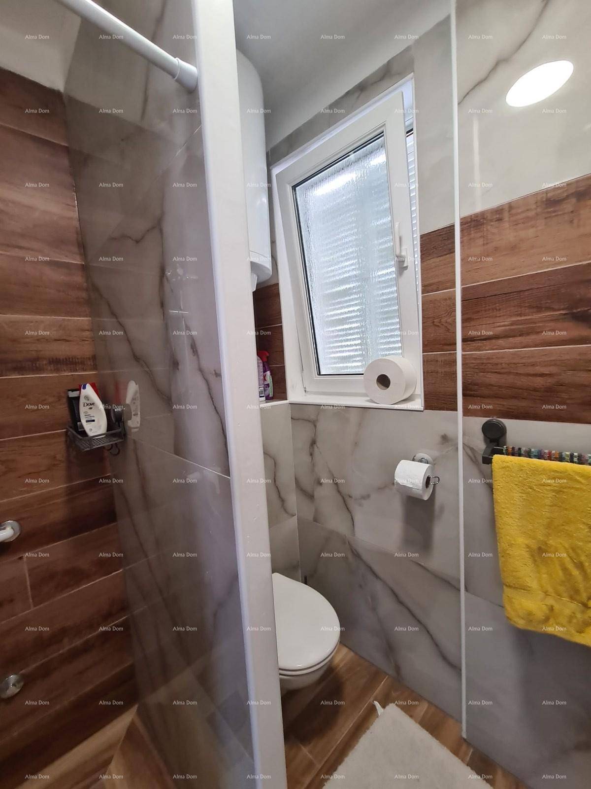 Modernes Badezimmer mit begehbarer Dusche, WC und Fenster, gefliest in Marmoroptik.