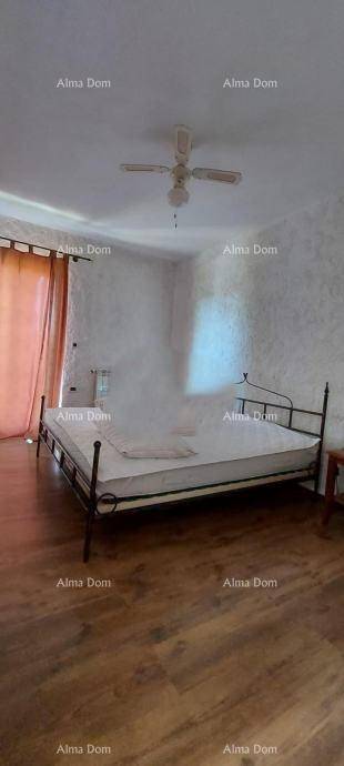 Schlafzimmer mit Doppelbett, Holzfußboden, weißen Wänden und Deckenventilator.