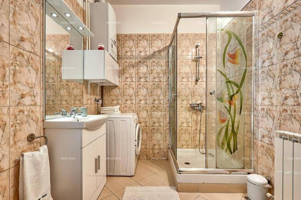 Badezimmer mit Dusche, Waschmaschine und gemusterten Fliesen an Wänden und Boden.