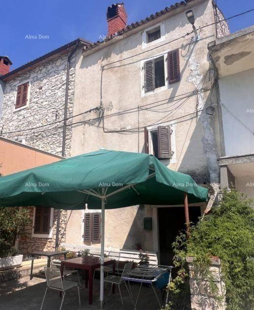 Traditionelles Steinhaus mit einer möblierten Terrasse und einem Grillbereich unter einem Sonnenschirm.