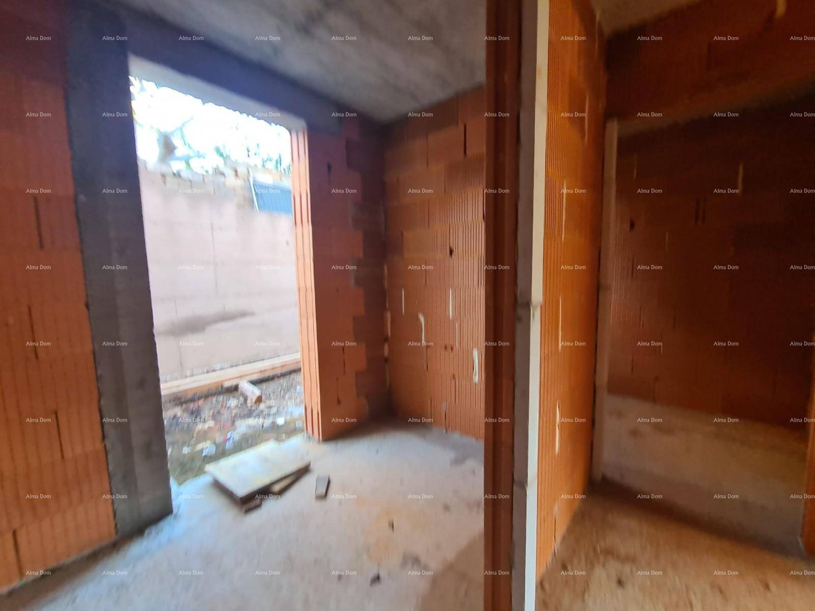 Rohbau eines Raumes mit Ziegelwänden und einem großen Fenster, das viel Tageslicht hereinlässt.