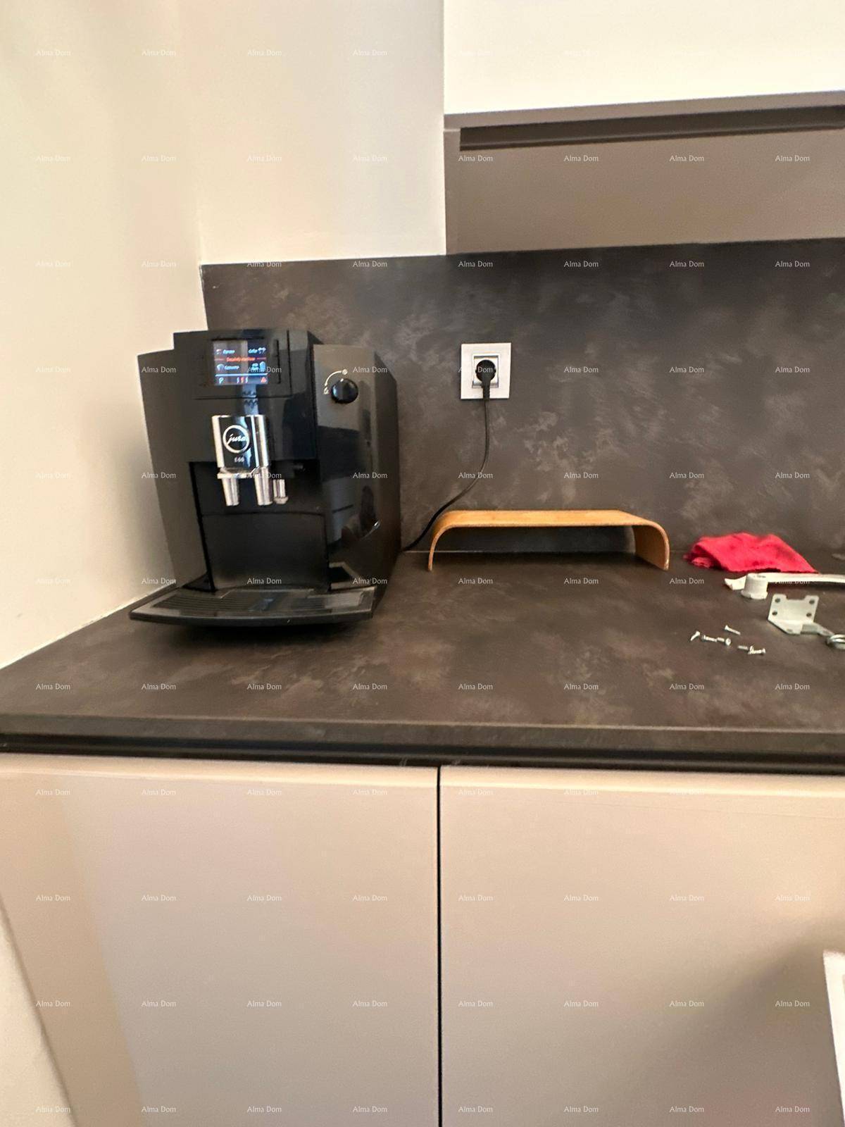 Moderne Kaffeemaschine auf einer dunklen Arbeitsplatte in einer hellen Küche.