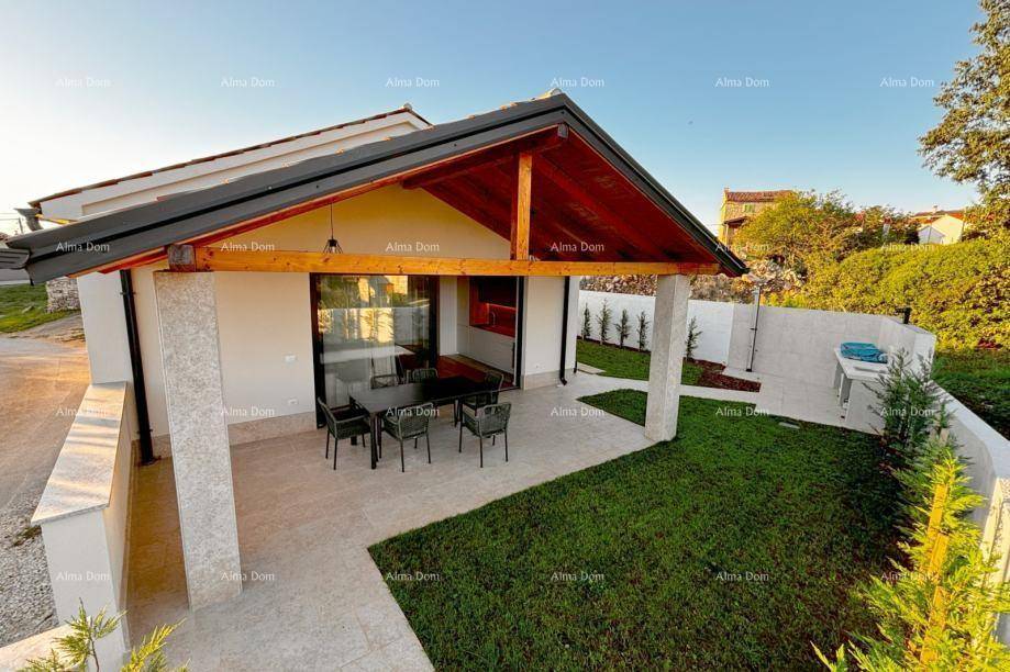 Hausfassade mit überdachter Terrasse, Holzbalken und angrenzendem Gartenbereich bei Sonnenuntergang.