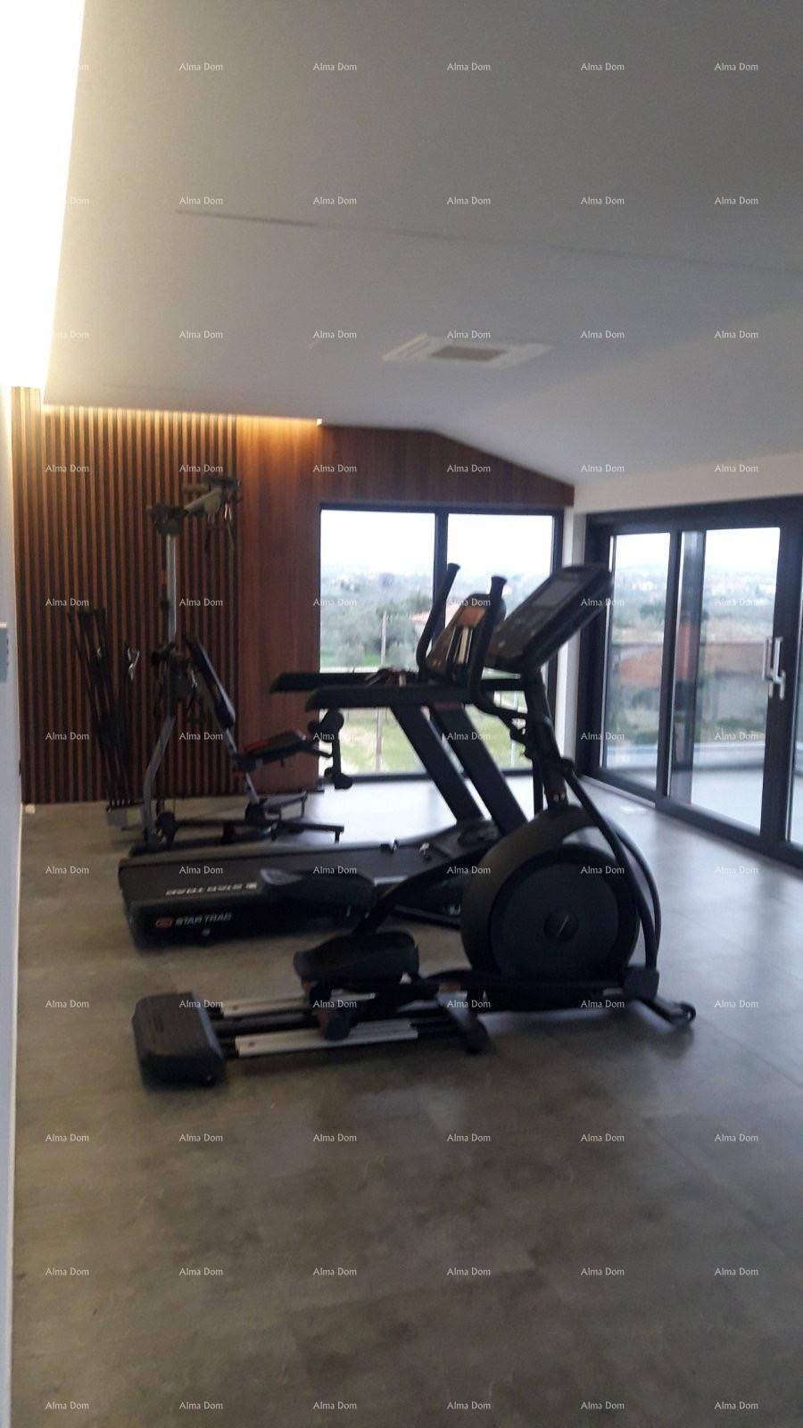 Heller Fitnessraum mit verschiedenen Trainingsgeräten und großen Fenstern.