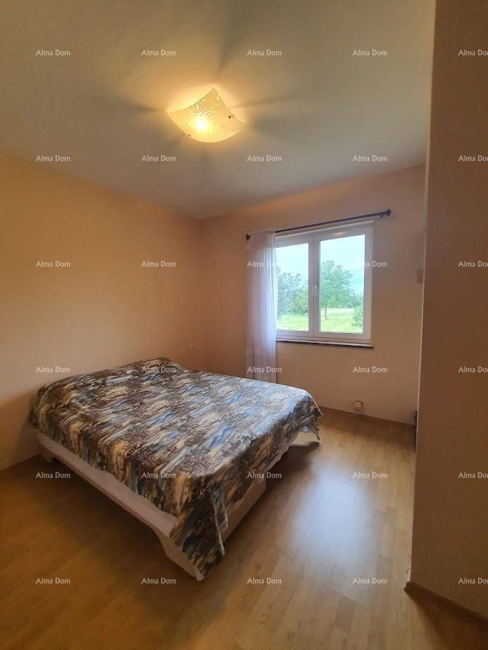 Helles Schlafzimmer mit Doppelbett, Holzboden und Fenster mit Blick auf die Landschaft.