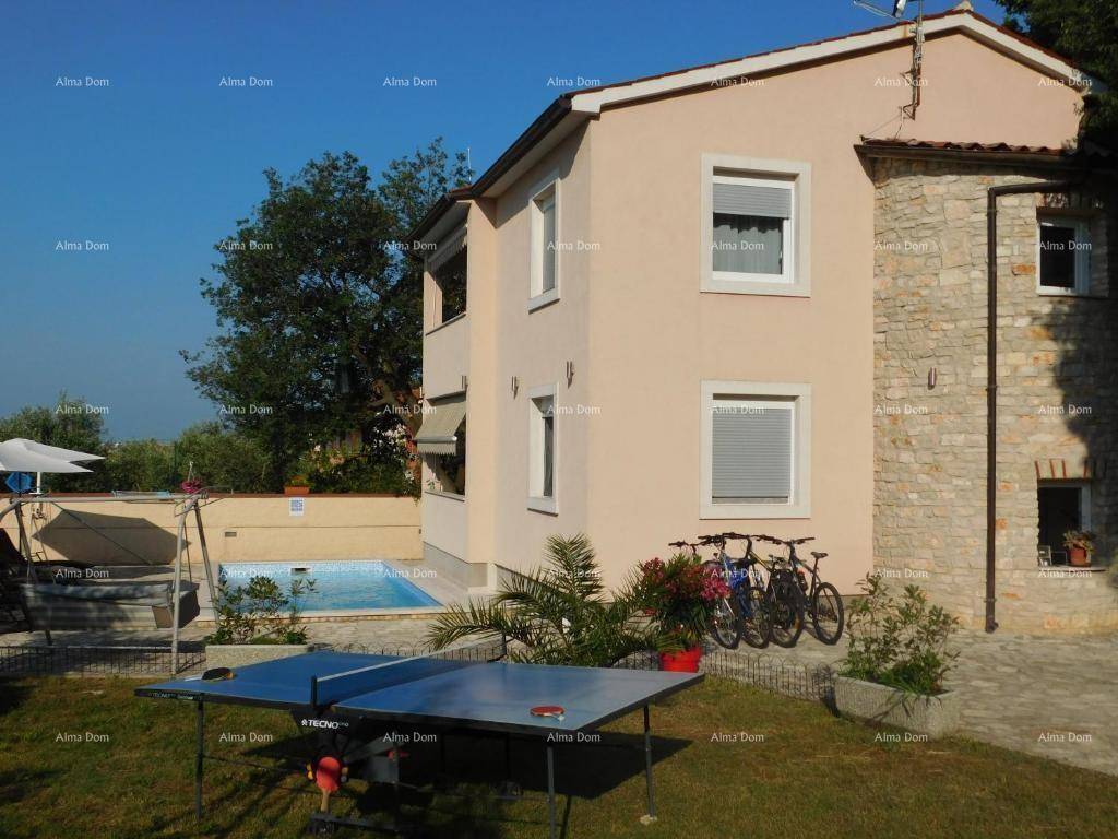 Hausfassade mit Poolbereich, Tischtennisplatte und Fahrrädern im sonnigen Garten. 