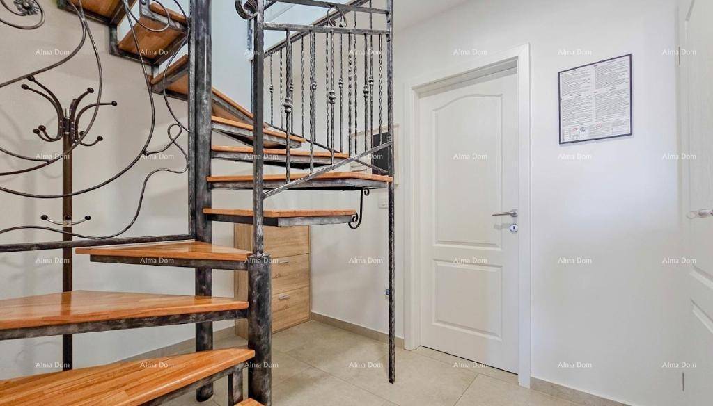 Heller Flur mit eleganter schmiedeeiserner Wendeltreppe und beigefliestem Boden.