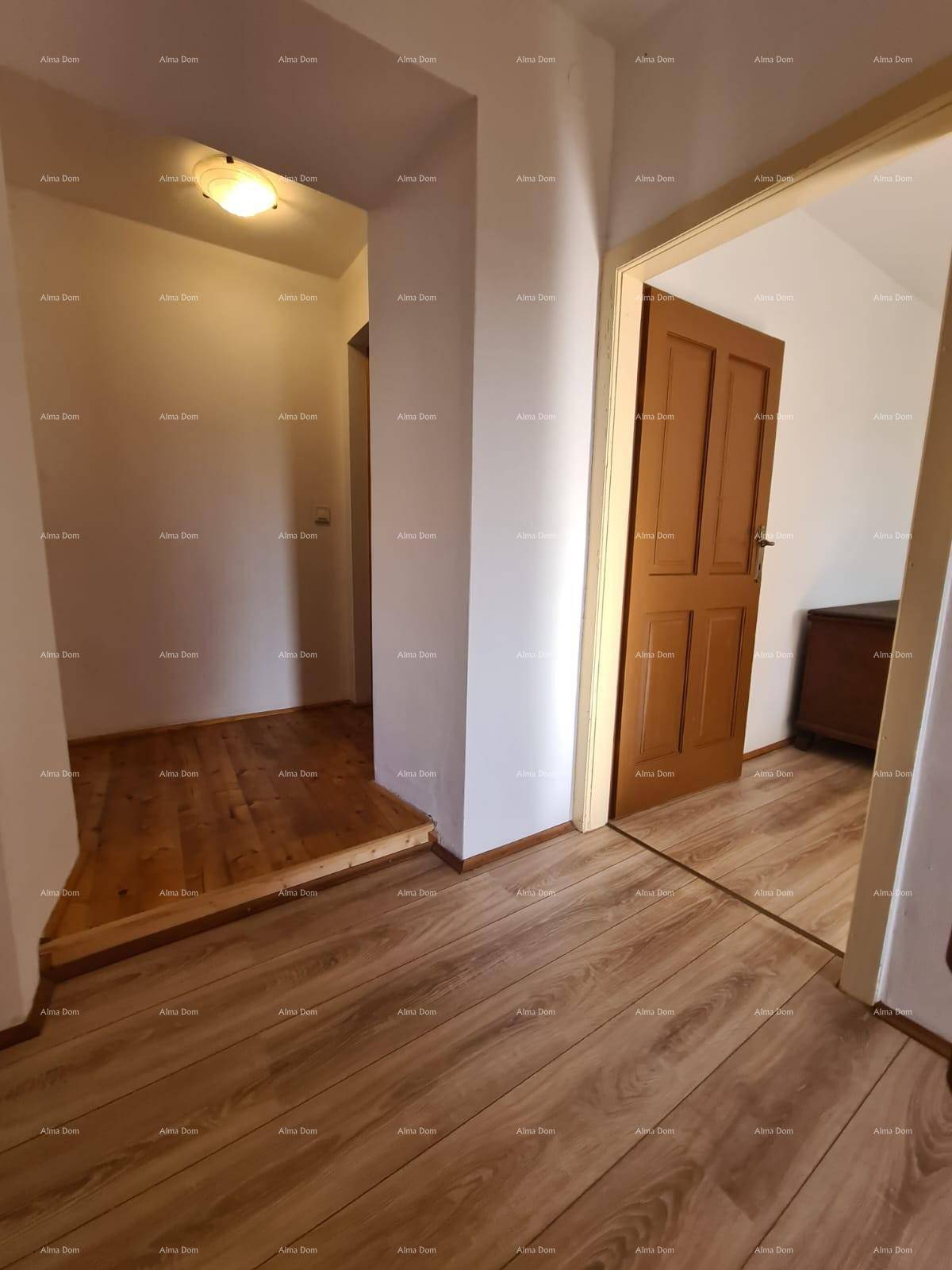 Flur mit Holzboden und Übergang zu einem Bereich mit Holztreppe, der die oberen Etagen verbindet.
