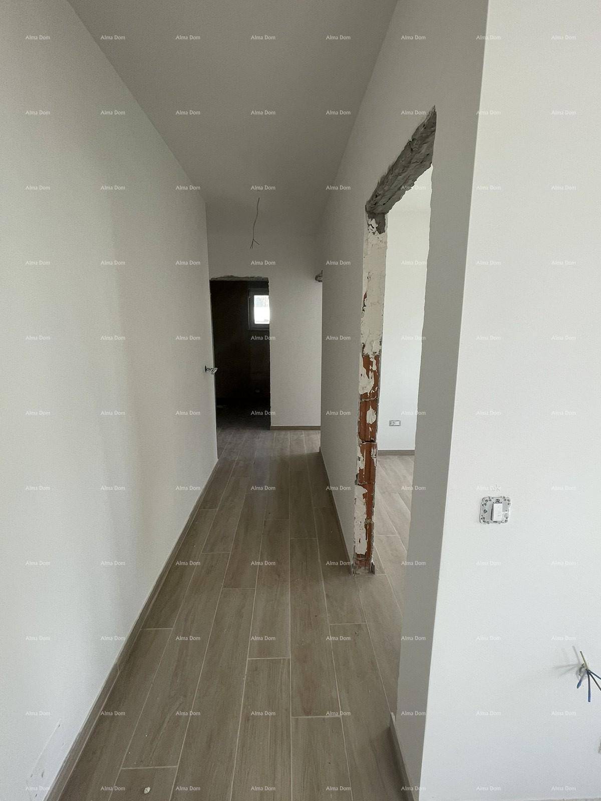 Langer, heller Flur im Rohbau mit Fliesenboden und weißen Wänden, der sich durch die Wohnung zieht.