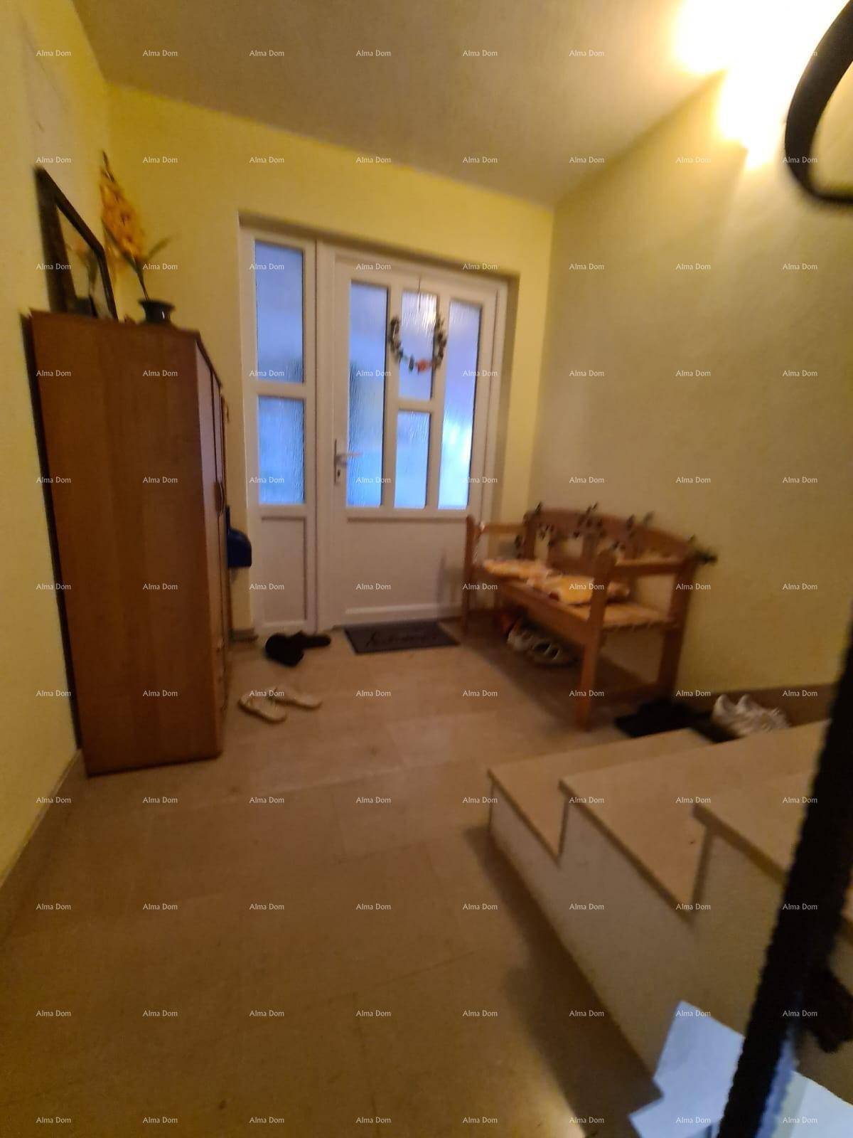 Eingangsbereich mit Holztür, Schrank und einer kleinen Bank, hell beleuchtet.