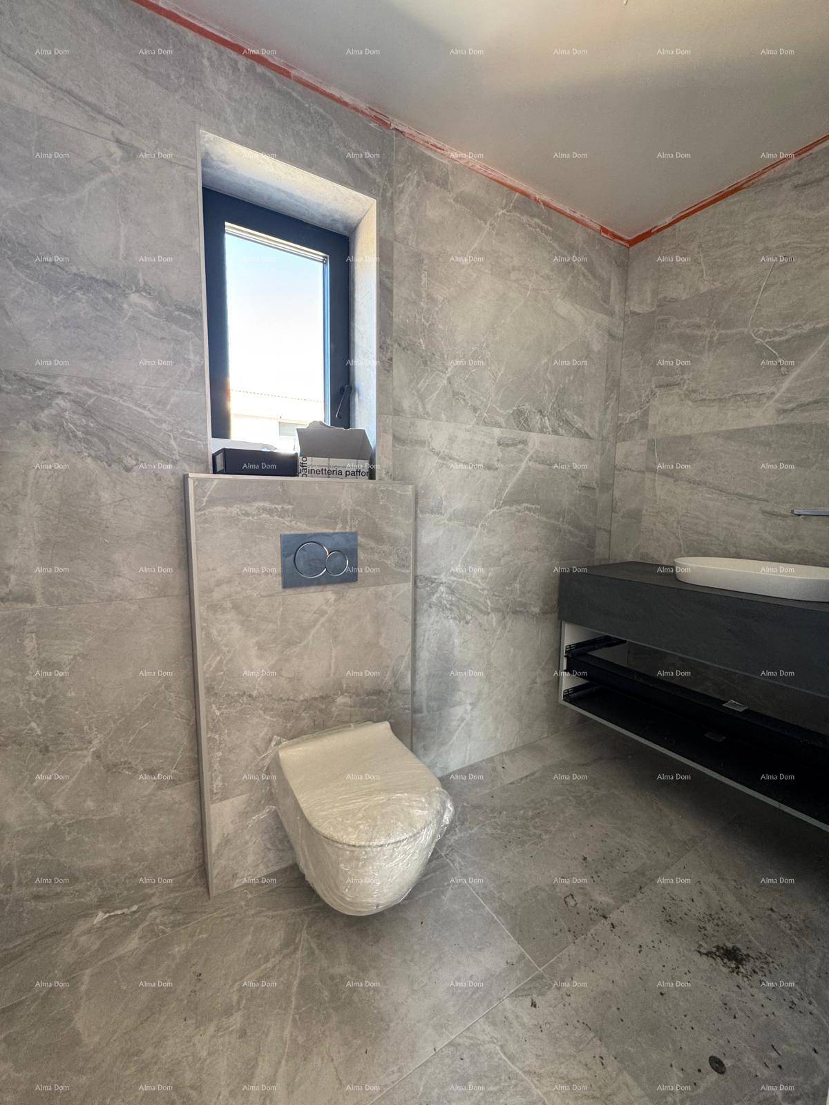 Modernes Badezimmer mit grauen Fliesen, wandhängendem WC und Fenster für Tageslicht.