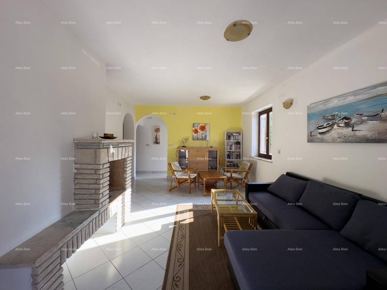 Helles Wohnzimmer mit Fliesenboden, Steinkamin und einer gelben Akzentwand, offen zu weiteren Räumen.