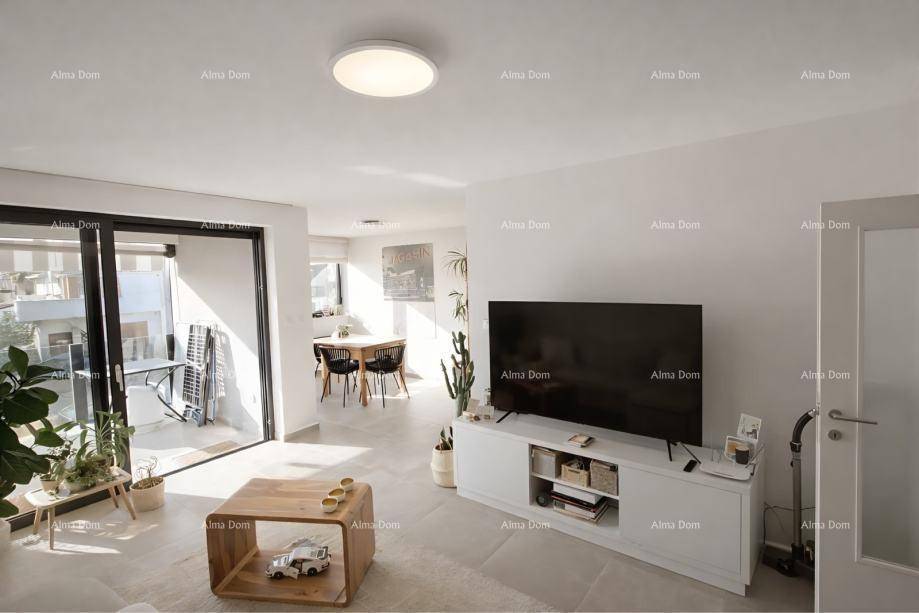 Moderner Wohnbereich mit Fernseher, Sofa und Essbereich im Hintergrund, mit Zugang zum Balkon.