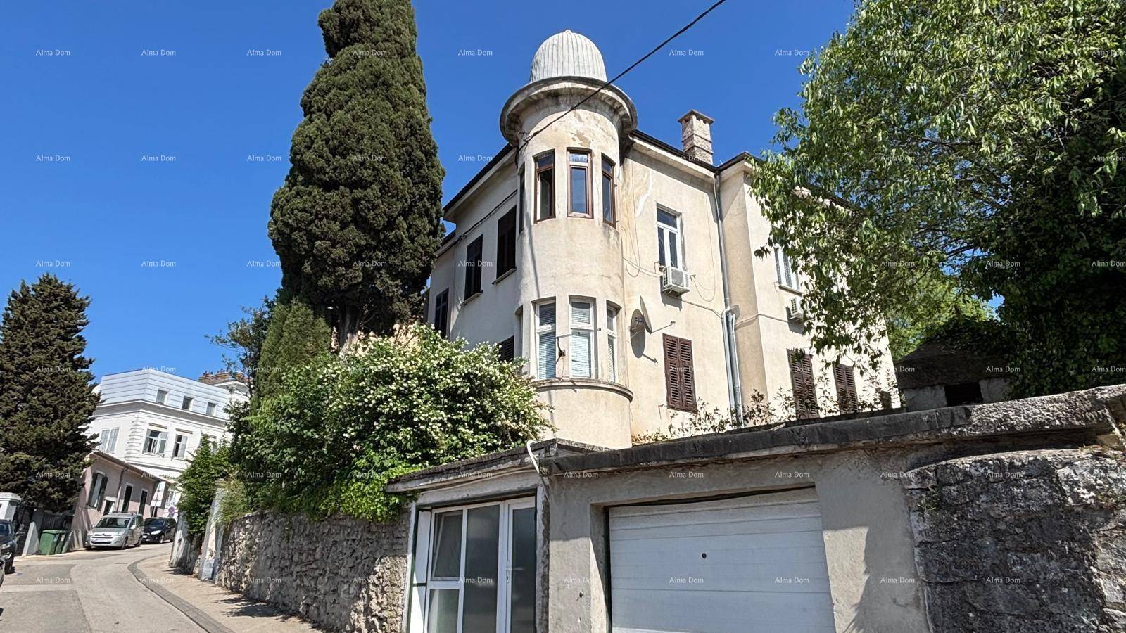 Ansicht des historischen Gebäudes von der Straße mit angrenzender Garage und charakteristischem Turm.