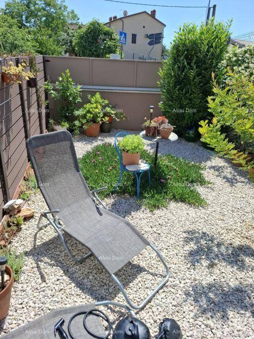 Gartenbereich mit Liegestuhl, Kiesboden und verschiedenen Topfpflanzen in sonniger Lage.