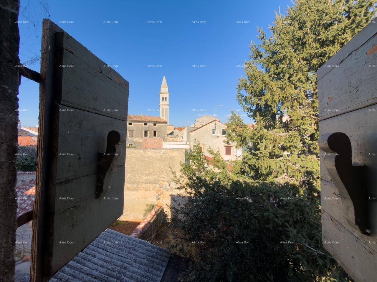 Blick aus einem Fenster mit geöffneten Holzläden auf einen Kirchturm und die umliegende Bebauung.