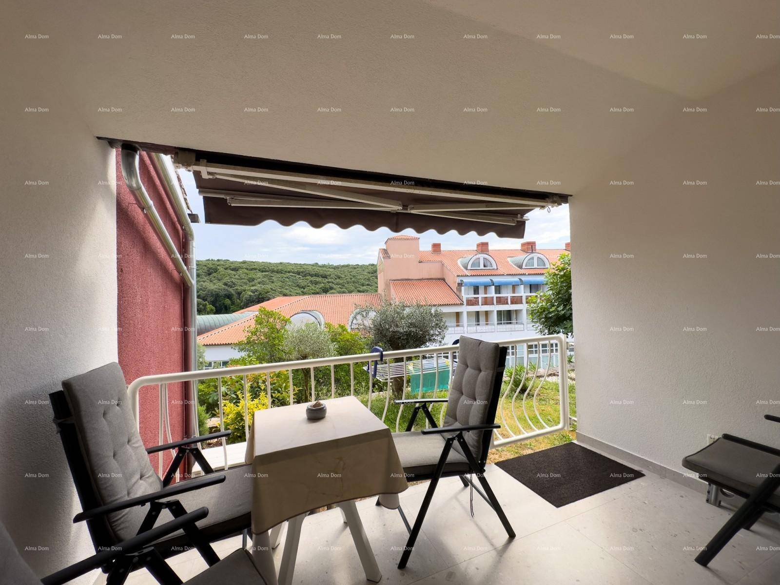 Möblierter Balkon mit Markise und Blick auf die umliegende Bebauung und grüne Landschaft.
