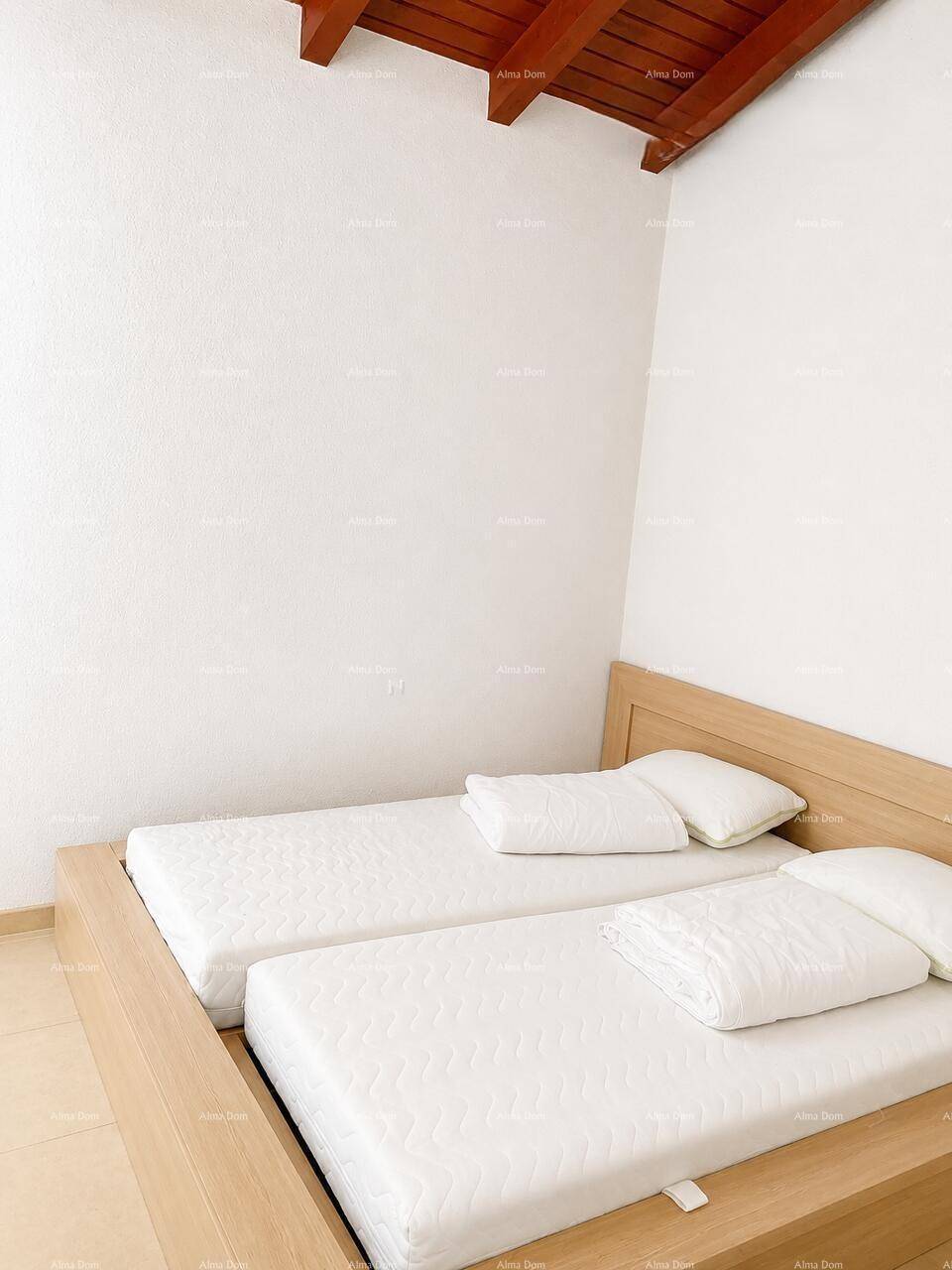 Schlafzimmer mit Holzbett und schräger Decke, bietet eine gemütliche und helle Atmosphäre.