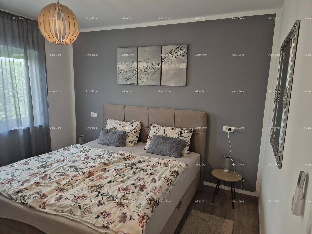 Gemütliches Schlafzimmer mit Doppelbett, grauer Akzentwand und Holzboden.