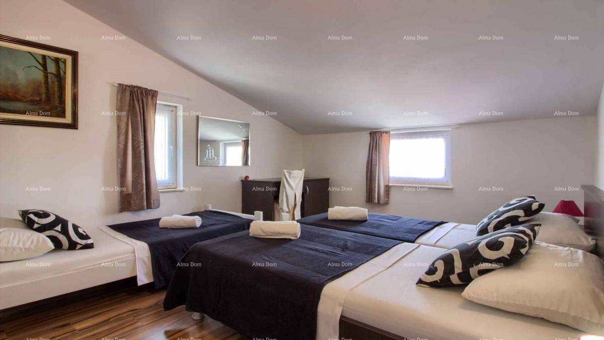 Geräumiges Schlafzimmer mit mehreren Einzelbetten, Holzboden und Dachschrägen.