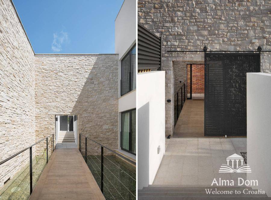 Architektonisch gestalteter Eingangsbereich mit Natursteinwänden und modernem Schiebetor.