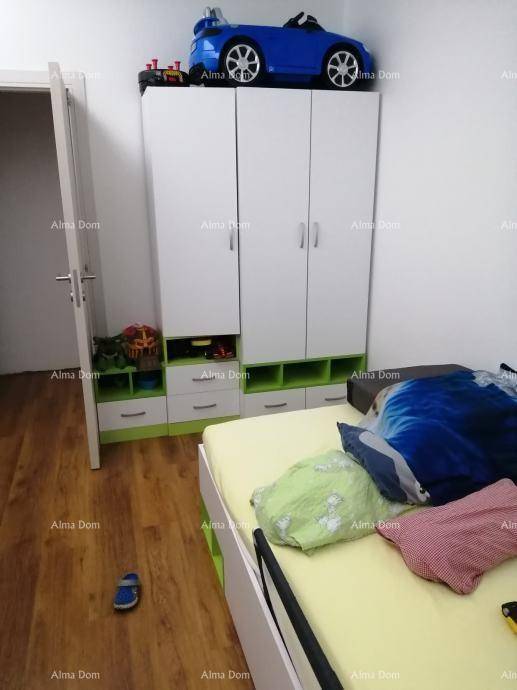 Kinderzimmer mit Bett, weiß-grünem Kleiderschrank und Spielzeug auf dem Boden.