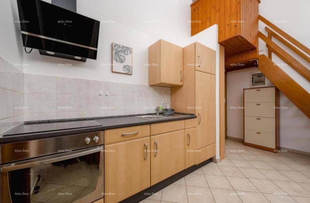 Kleine Küche mit Holzschränken, integrierten Geräten und Treppe zu einer oberen Ebene.