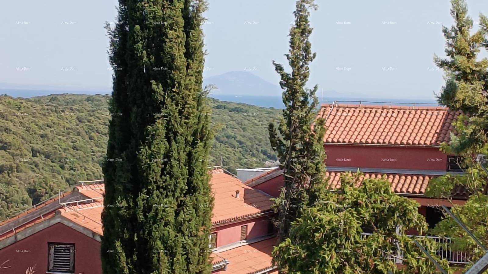 Panoramablick auf die bewaldete Landschaft, rote Dächer und das Meer in der Ferne.