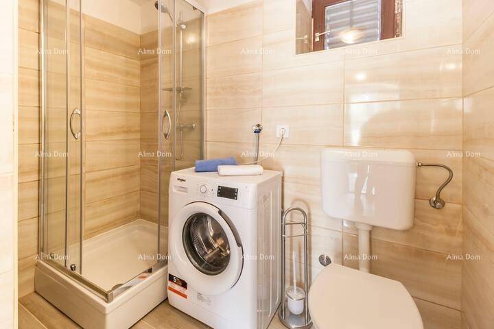 Modernes Badezimmer mit Duschkabine, Toilette und Waschmaschine, hell gefliest.