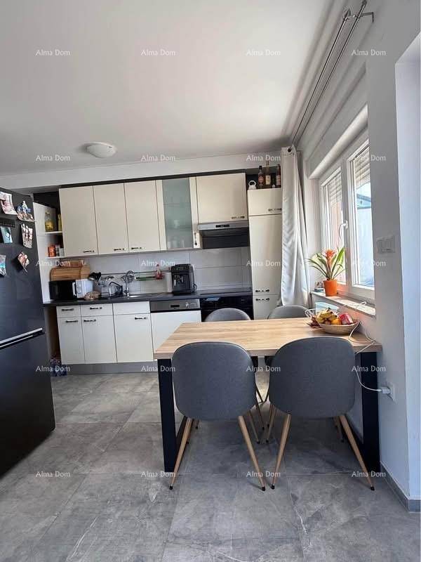 Moderne Einbauküche mit weißen Schränken, Essbereich und Fenster.