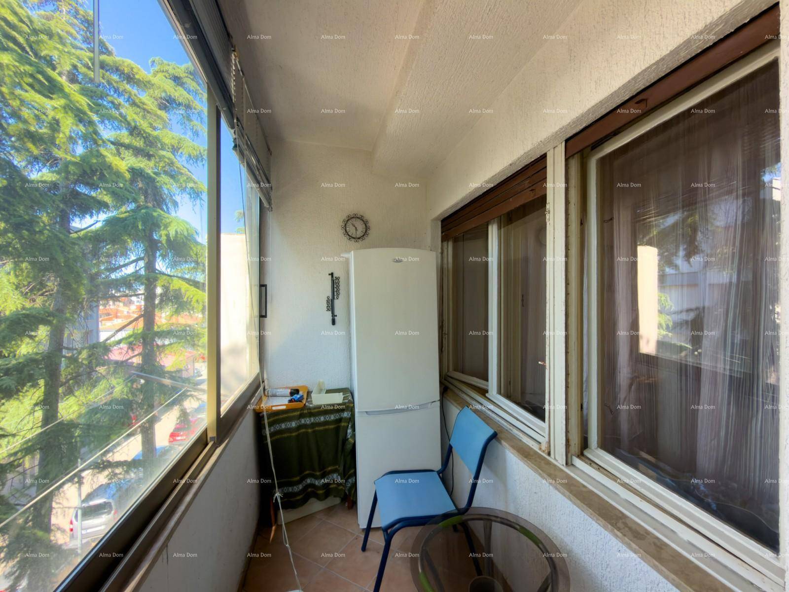 Verglaster Balkon mit Kühlschrank, Tisch und Stühlen, bietet einen grünen Ausblick.