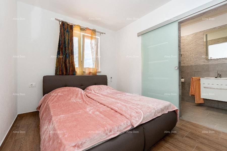 Schlafzimmer mit Doppelbett und Schiebetür, die zu einem modernen Badezimmer führt.