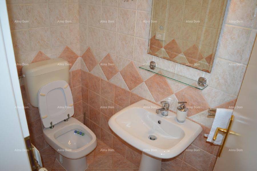 Kleines Gäste-WC mit Waschbecken und Toilette, dekoriert mit beigen und rosa Fliesen.