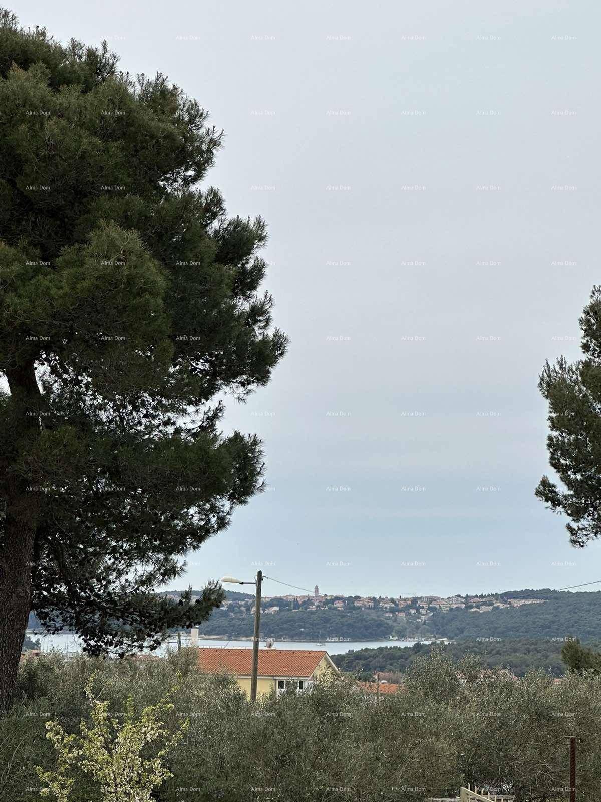 Weitläufiger Blick auf die Küstenlandschaft mit Meer, Bäumen und einer kleinen Stadt in der Ferne.