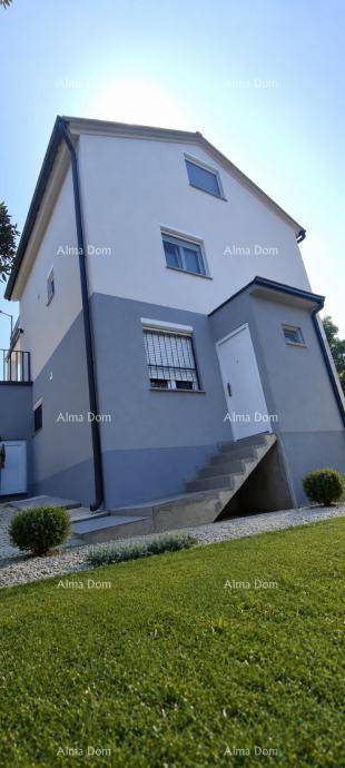 Außenansicht eines modernen Hauses mit weißer und grauer Fassade und gepflegtem Rasen.